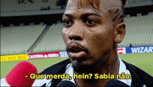 a man talking into a microphone with the words que merda hein sabia não written below him
