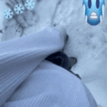 a person is standing in the snow with snowflakes and a blue face emoji .
