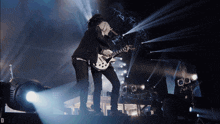 a man singing into a microphone while holding a guitar on a stage