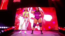 a couple of women are standing on a stage in front of a large screen .