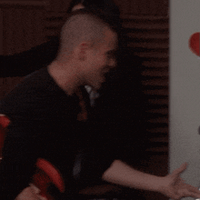 a man and a woman standing next to each other with a red heart on the wall