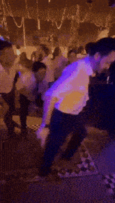 a group of people are dancing in a dark room