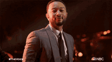 a man in a suit and tie is standing in front of a nbc ad
