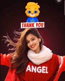a woman wearing a red angel sweater is smiling with a thank you sticker on her head