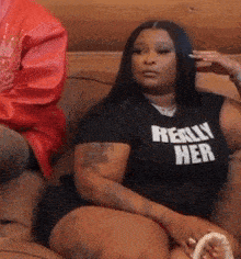 a woman is sitting on a couch wearing a really her t-shirt