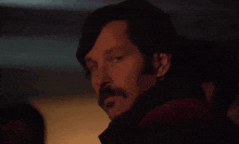 a man with a mustache is looking at the camera