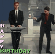 a man in a suit is playing a keyboard and another man is dancing in front of a happy birthday sign