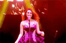 a woman is singing into a microphone on a stage