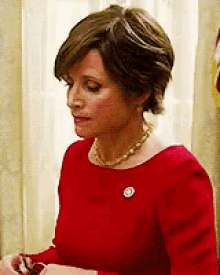 a woman wearing a red dress and a pearl necklace