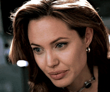 a close up of a woman 's face wearing earrings and a necklace