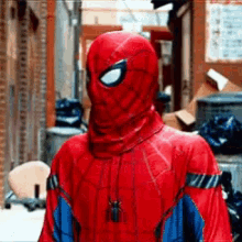 a man in a red spiderman costume is standing in an alleyway