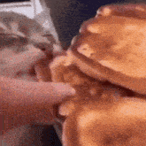 a close up of a person 's hand touching a stack of pancakes .
