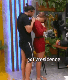 a man is standing next to a woman in a red dress with the words @tvresidence written on the bottom