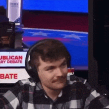 a man wearing headphones is sitting in front of a television screen that says republican debate