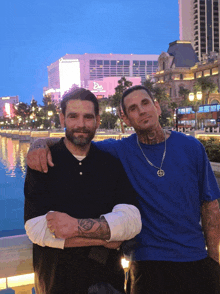 two men are posing for a picture in front of a building that says the bellagio