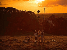 a group of people standing in a field at sunset with a sign that says ' i love you '