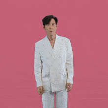 a man in a white suit is making a funny face with his hands on his ears