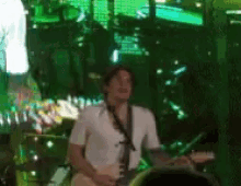 a man in a white shirt is playing a guitar in a dark room