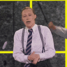 a woman in a striped shirt and tie is clapping .