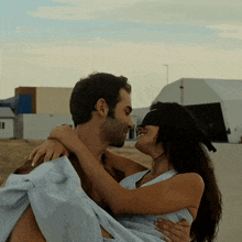 a man is carrying a blindfolded woman in his arms and they are kissing
