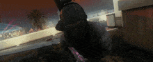 a man in a mask is holding a gun in front of a building with a palm tree in the background
