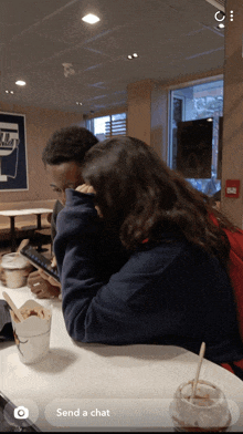 a man and a woman are sitting at a table in a restaurant with the words send a chat below them