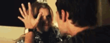 a man and a woman are standing next to each other and covering their faces with their hands .
