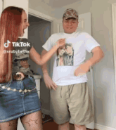 a man and a woman are standing next to each other and the man is wearing a tiktok shirt