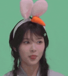 a girl wearing a headband with a carrot on it sticking her tongue out .