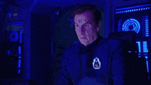 a man in a space suit with the letter h on his forehead is making a funny face .