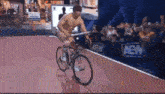 a shirtless man is riding a bicycle on a track in front of a crowd .