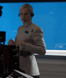a woman wearing a headset is standing in front of a blue background