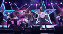 a group of people are dancing on a stage in front of stars