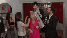 a woman in a pink dress is being helped by a man in a suit