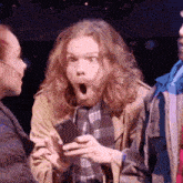 a man with a surprised look on his face is holding a cellphone