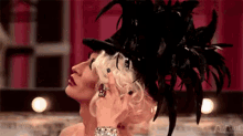 a woman wearing a top hat with feathers on it is standing next to another woman wearing a top hat .
