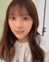 a close up of a woman 's face with long brown hair and a white shirt
