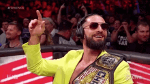 a man wearing headphones and sunglasses is holding a world heavyweight wrestling championship belt .
