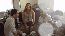 a group of people are sitting around a table and one of them has a tattoo on her chest that says ' a ' on it