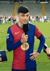 a man wearing a nike shirt is holding a microphone on a field