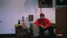 a man in a red shirt sits on a zebra print chair