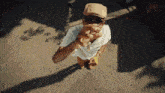 a man wearing a hat and sunglasses is standing on a street .