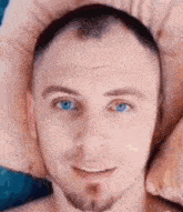 a man with blue eyes and a beard is smiling and looking at the camera