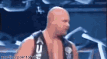 a bald wrestler with a skull on his vest stands in front of a blue background with anotherpointofview written on it
