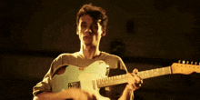 a man in a green shirt is playing a guitar in a dark room