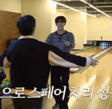 two men are standing on a bowling alley with the number 1 on the wall