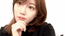 a close up of a young woman 's face with her hand on her chin .