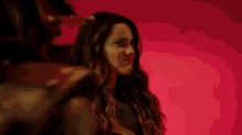 a woman is making a funny face in front of a red wall .
