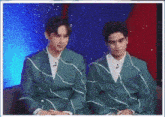 two men in green suits are sitting next to each other on a chair .