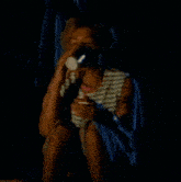 a woman in a striped shirt is sitting in the dark holding a can of soda